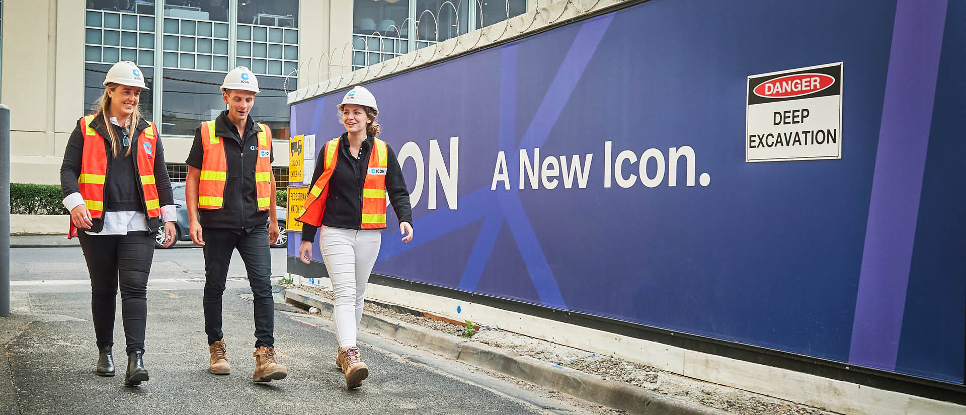 Icon team members walking past a project hoarding on site