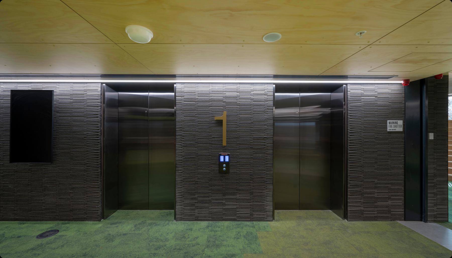 Lift lobby finished in dark timber panelling